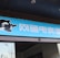 A building entrance features a vibrant blue sign with white Chinese characters and a stylized orca logo in black and white. The overall appearance suggests an establishment focused on eSports or digital activities.